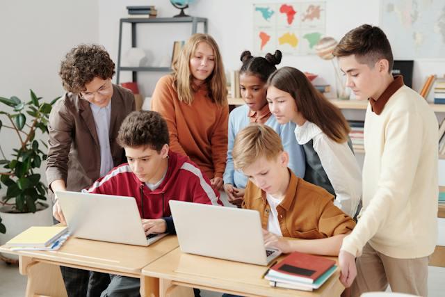 A group of children work on computers in a classroom